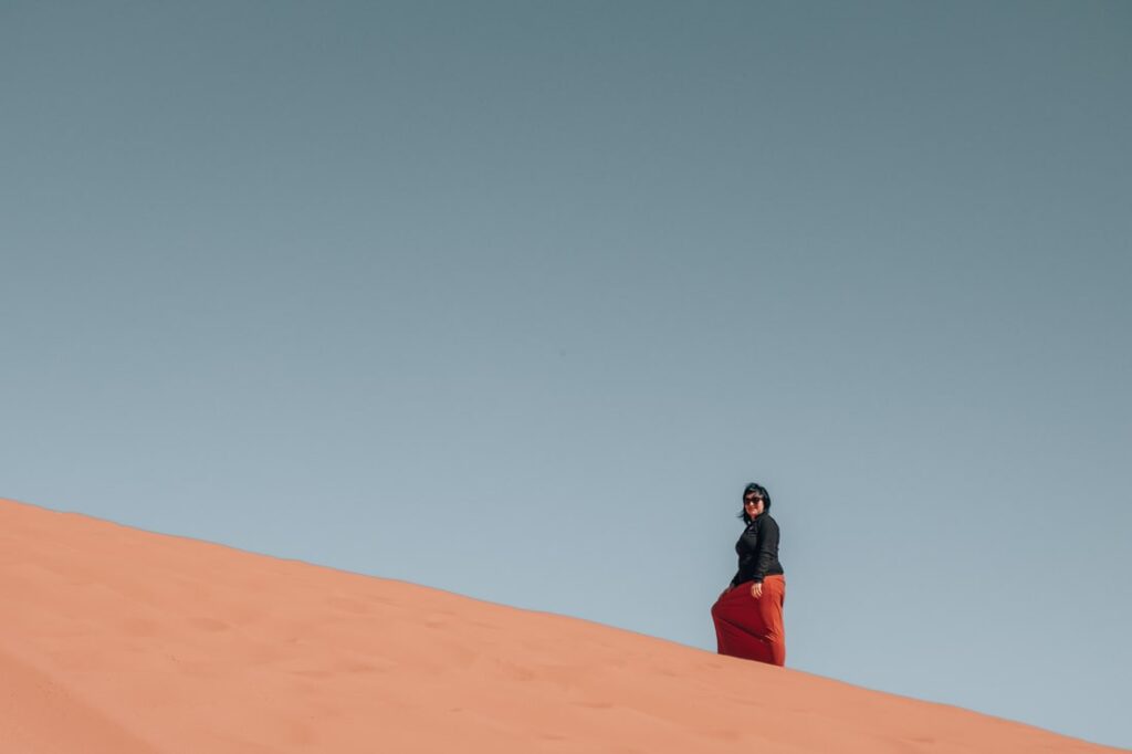 Mieke climbing a red sand dune
