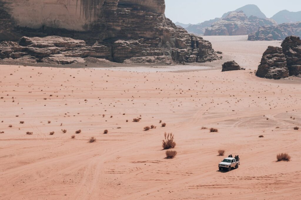 jeep driving in the distance through a huge desert