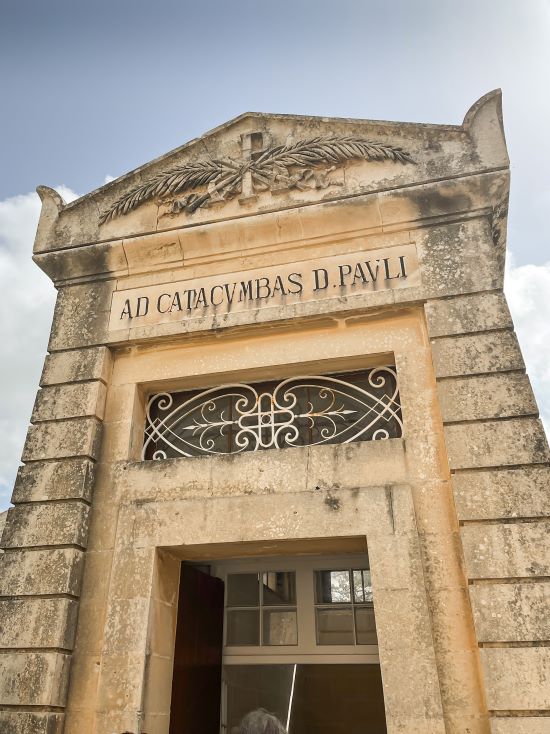 Entrance gate with a decoration at the top and the text Ad Catacumbas D. Pauli
