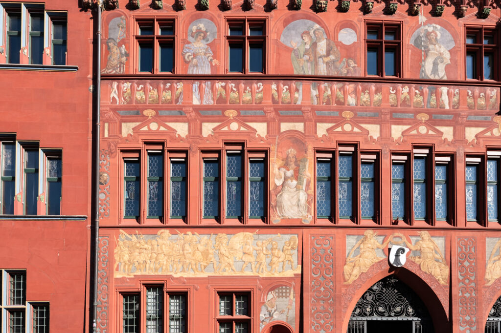 The colorful red front of the town hall in Basel in Switzerland, with many paintings on it
