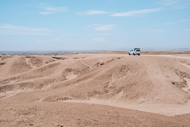 White 4x4 pickup truck parked along the moon landscape canyon in the Namib Desert at the Welwitschia drive near Swakopmund